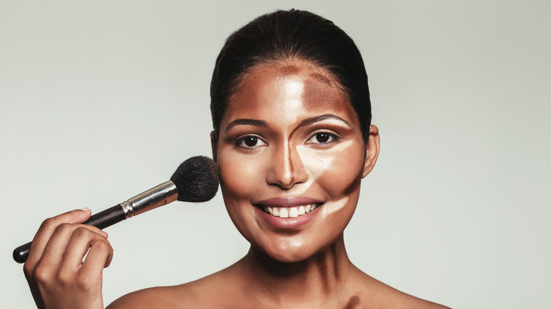 woman applying makeup contour with brush