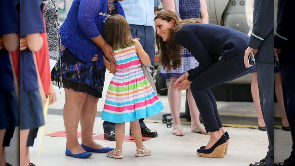 Kate Middleton in wedges speaking to girl