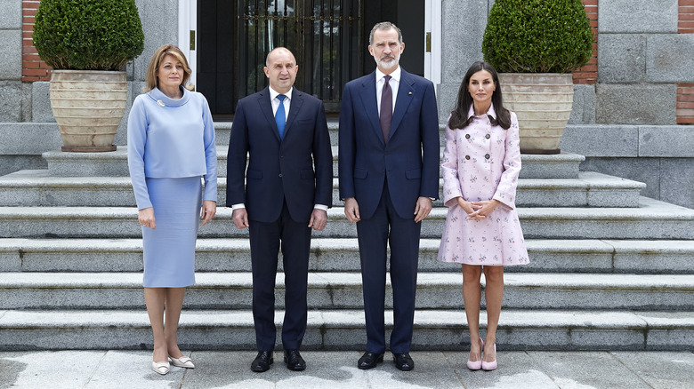 Queen Letizia standing with her husband and their guests, Letizia wearing a pink coat,