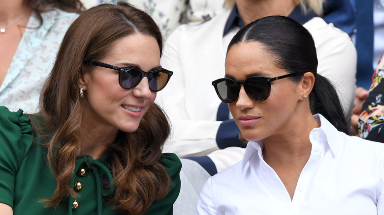 Meghan Markle wearing sleek black sunglasses at Wimbledon with Kate Middleton