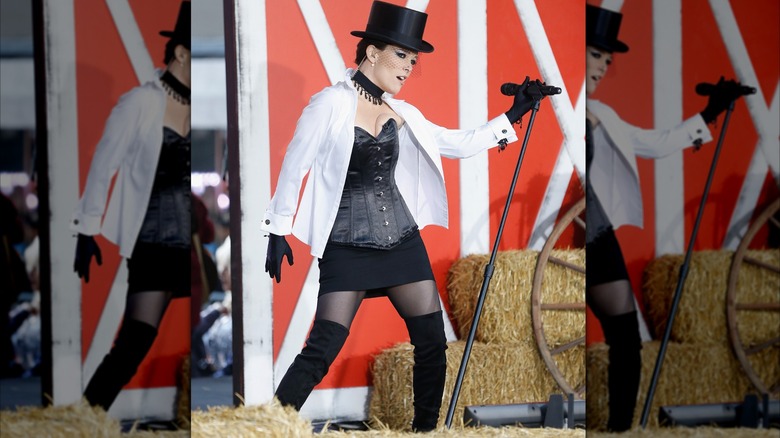 Megyn Kelly dressed like Shania Twain, with top hat and corset, behind a mic.