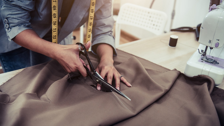 Fashion designer cutting fabric