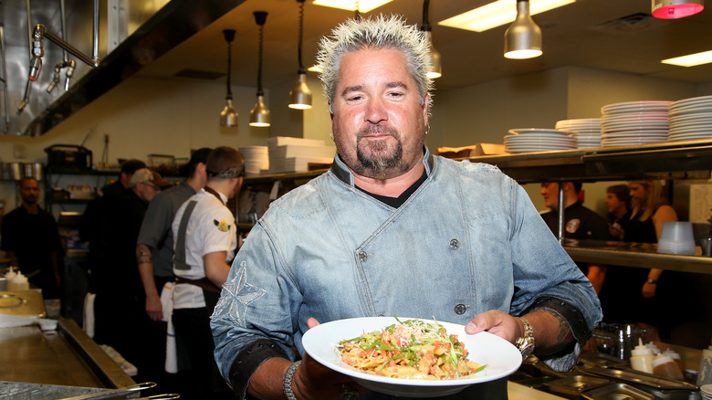 Guy Fieri holding a plate of pasta