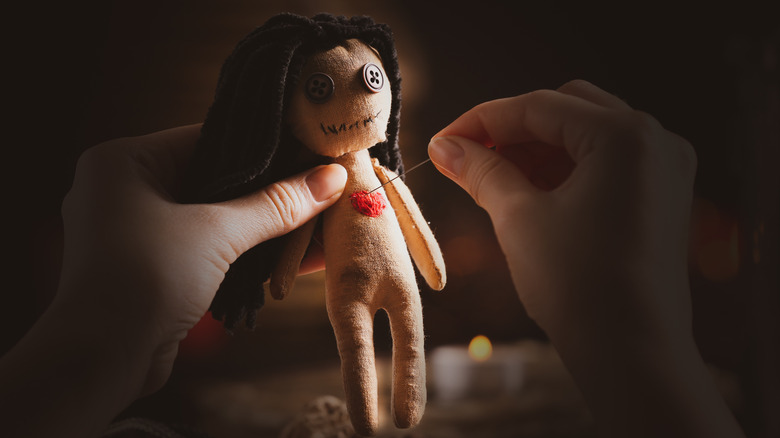 person poking voodoo doll