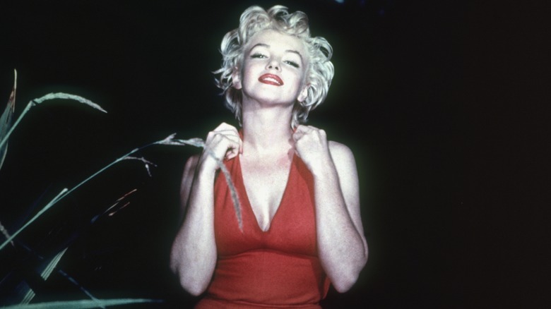 Marilyn Monroe tilts her head back and poses for a photo