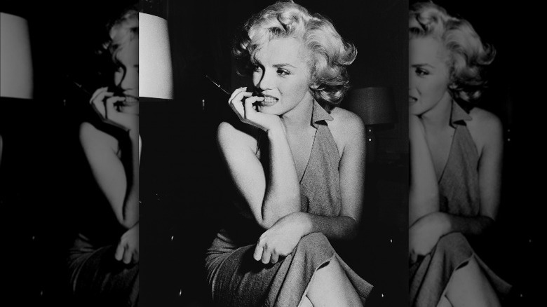 Black and white shot of Marilyn Monroe sitting down with her chin in the palm of her right hand