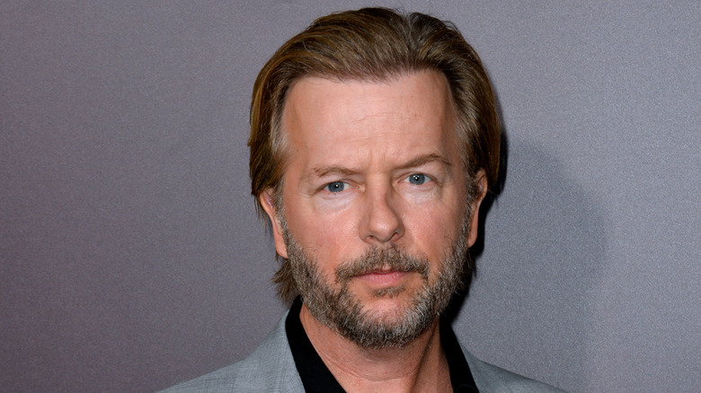 David Spade wearing a gray suit.