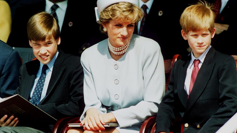 Princess Diana sits at an event with Prince Harry and Prince William