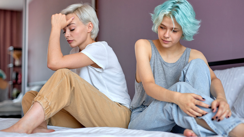 two distressed women sitting on bed