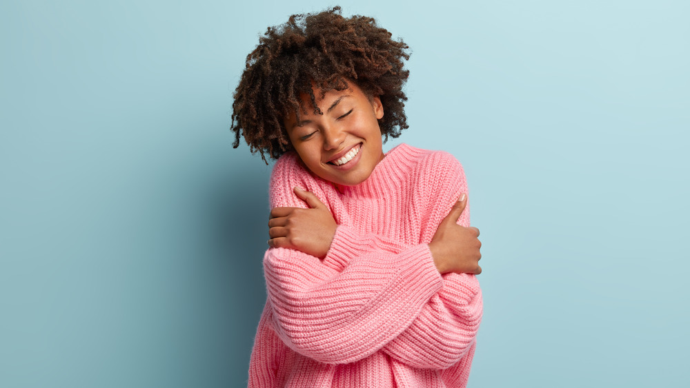 Woman in pink sweater hugging herself