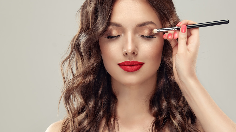 Woman with red lipstick getting makeup done