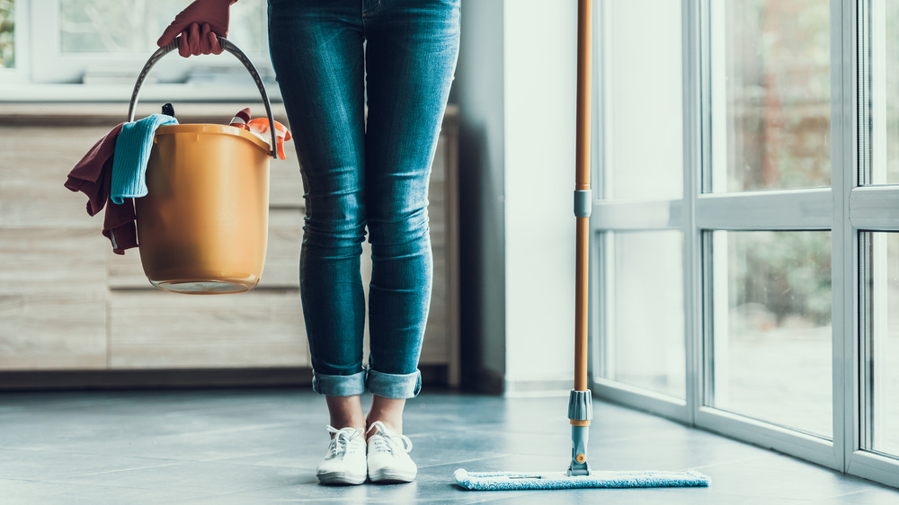 Woman holding mop and bucket