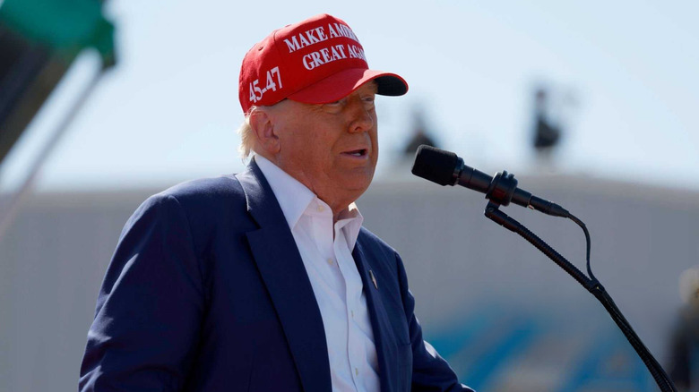 Donald Trump speaking while wearing a MAGA hat