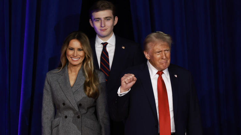 Melania and Barron Trump smiling and Donald Trump grimacing