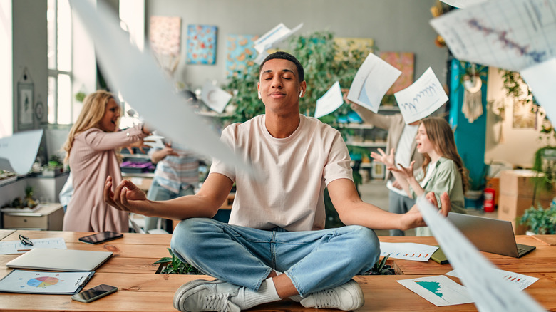 A man meditating amongst paperwork.