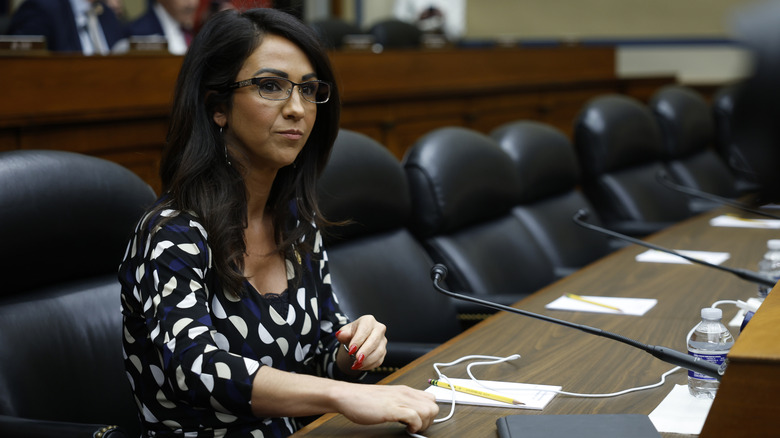 Lauren Boebert sitting behind a desk and a microphone