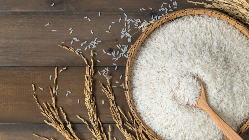 Uncooked rice in a bowl with a wooden spoon