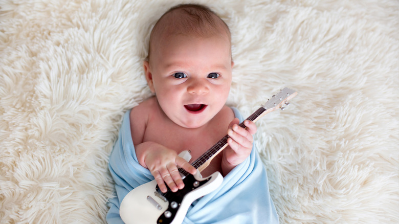 Baby boy holding tiny guitar