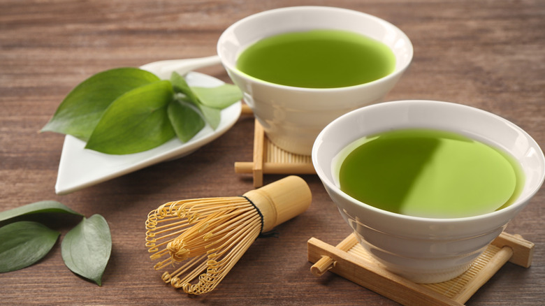 Cups of matcha tea with a matcha whisk