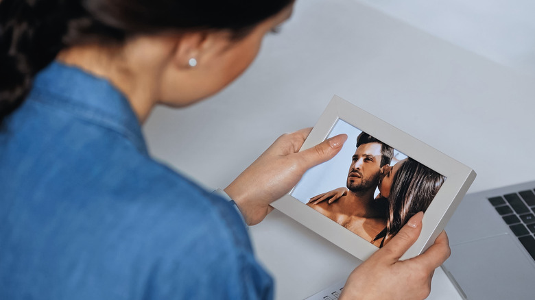 A person holding up a photo of a couple