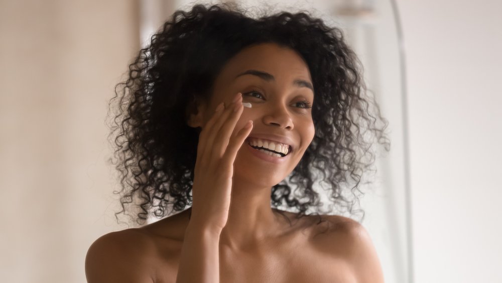 A woman applying cream to her face