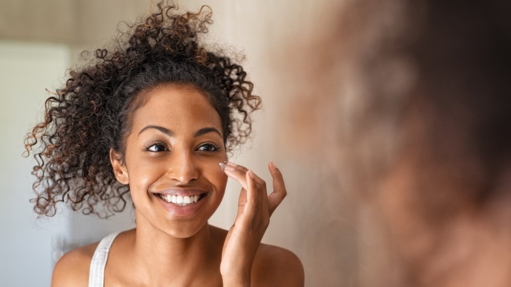 A woman applying skincare products to her face