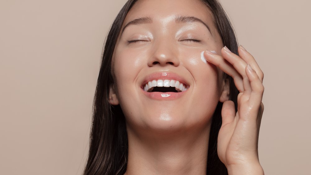 A woman applying cream under her eye