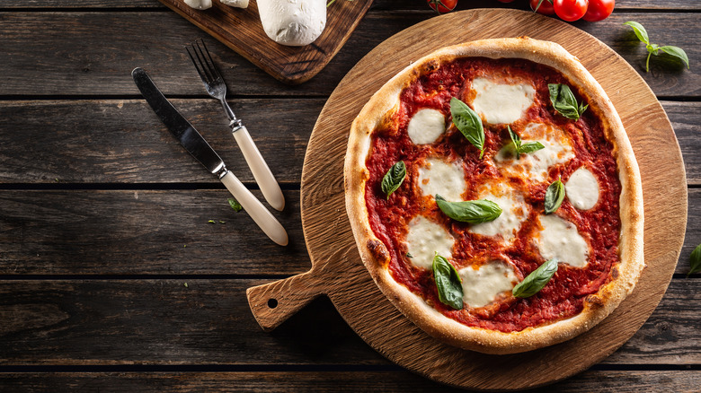 Margherita pizza on a cutting board with cutlery