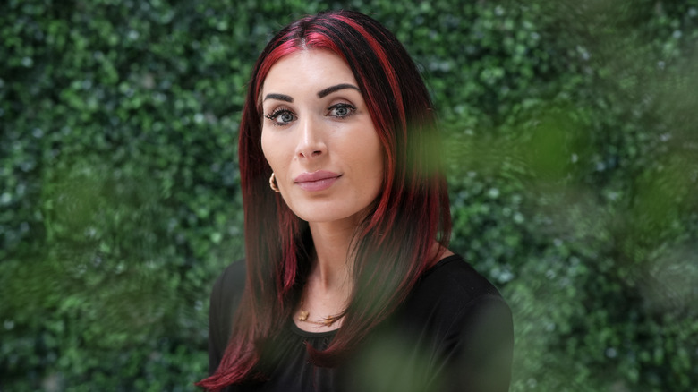 Laura Loomer poses in front of greenery