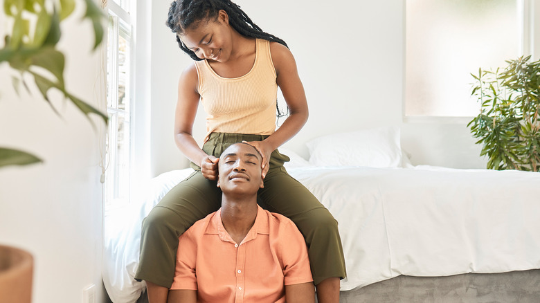 Woman massages man's scalp