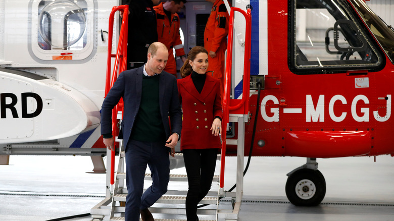 Prince William and Kate Middleton in front of a helicopter. 