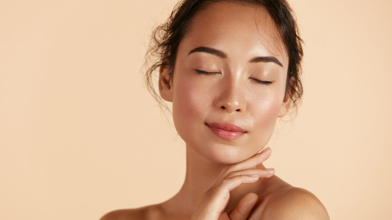 Woman touching her face with her eyes closed