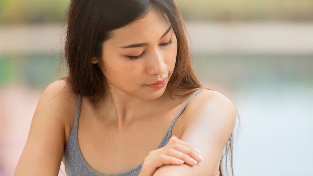 Woman inspects her arm's skin