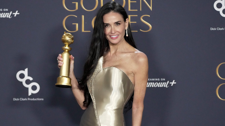 Demi Moore smiling and holding her Golden Globe award