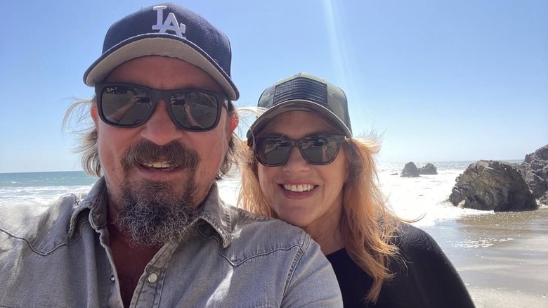 James Jordan and Debra Schrey smiling on the beach wearing baseball caps