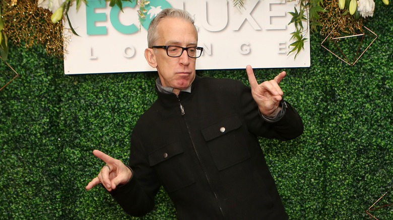 Andy Dick posing in front of a sign