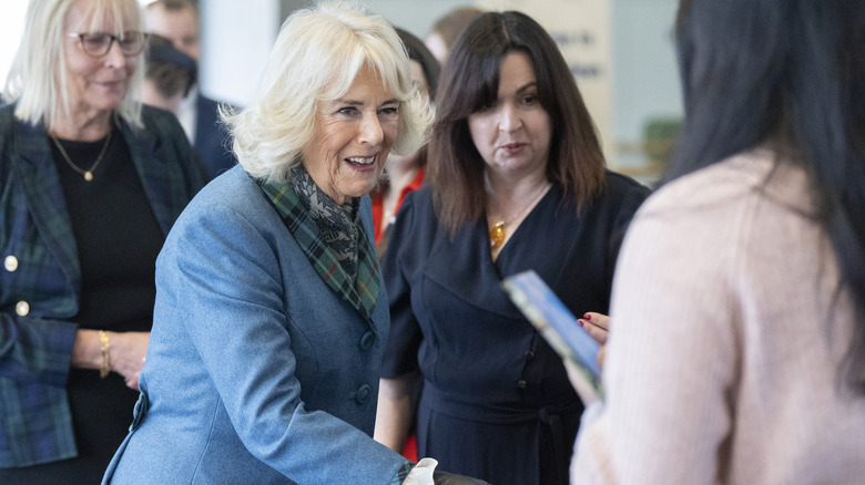 Queen Camilla smiling and shaking hands