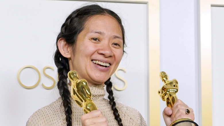 Chloe Zhao holding two Oscars