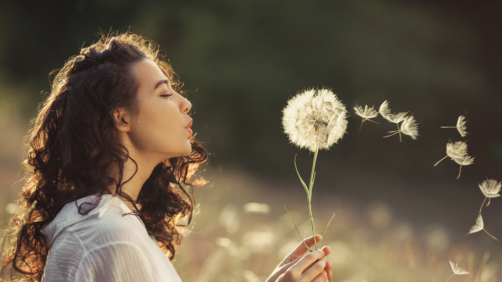 Woman blowing dandelion 