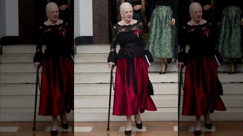 Queen Margrethe walking in a black lace dress and cane