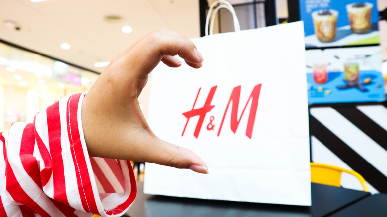 Woman making heart with hand over H&M bag