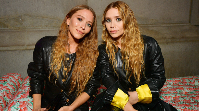 Mary-Kate and Ashley Olsen sitting together on a couch