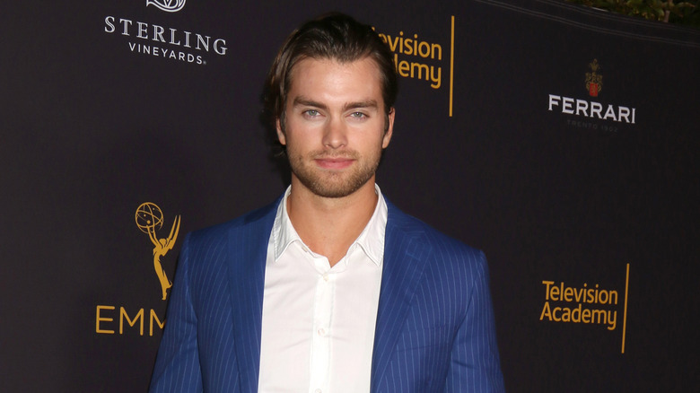 Pierson Fode poses for the camera while wearing a white button down shirt and blue pin-striped suit.