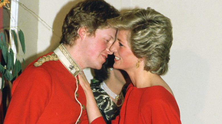 Charles Spencer and Princess Diana, he in red military coat, she in a red dress. Their heads are together in an intimate conversation.