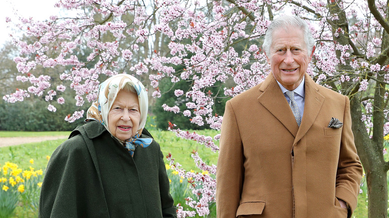 Queen Elizabeth wearing head scarf and Prince Charles in camel coat