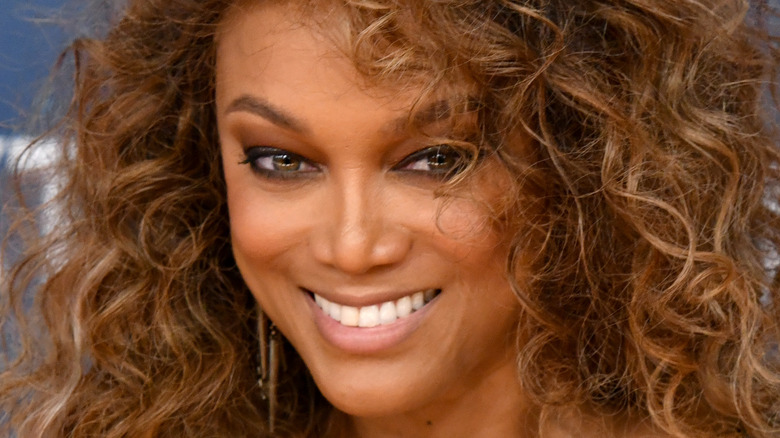 Tyra Banks smiles big with large curls.