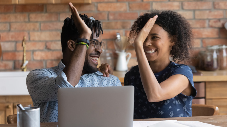 couple high-fiving by a computer