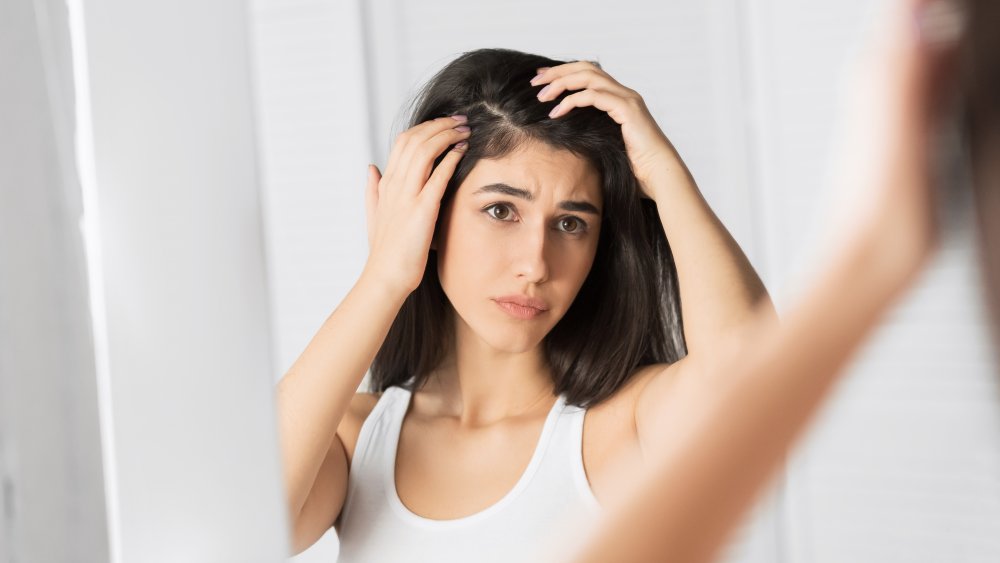 woman looking at her scalp in a mirror