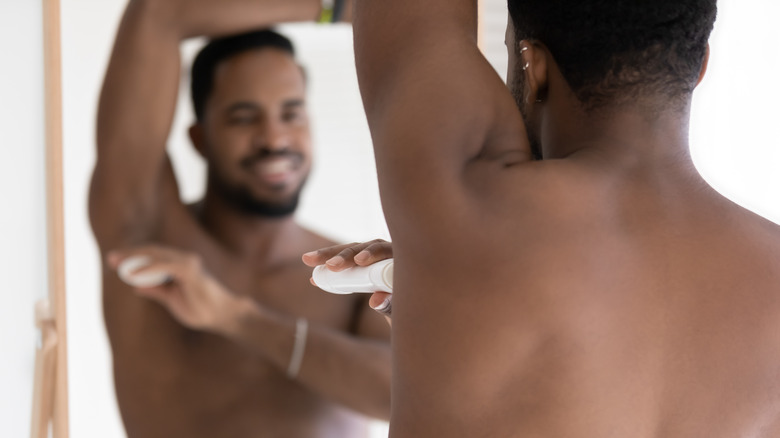 man applying deodorant on armpit