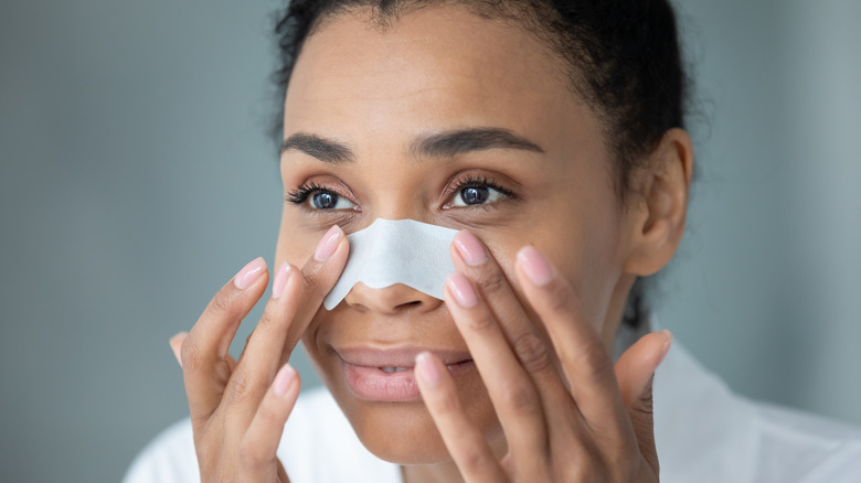 Woman putting strip on her nose